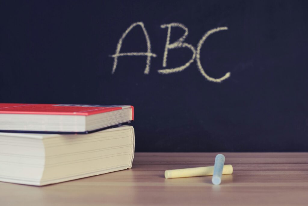 Blackboard with the letters ABC in the background, books and a pen in front of the blackboard