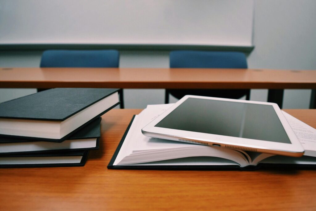 Picture of a classroom with several notebooks stacked on top of each other and an iPad on top of an open notebook